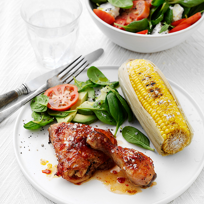 Spicy kyllingelår med grillede majskolber og sommersalat